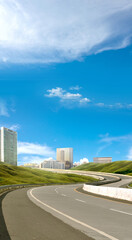 Fototapeta premium Asphalt road with green grass and cityscape