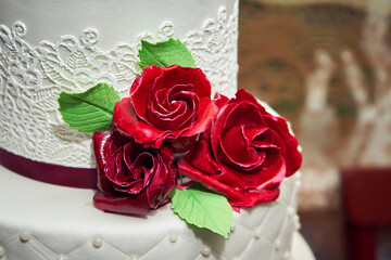 Close-up of decoration with edible flowers in red tones on a cake