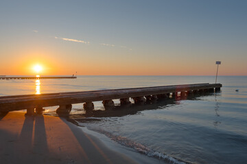 view of the rising sun on the beach with a pier