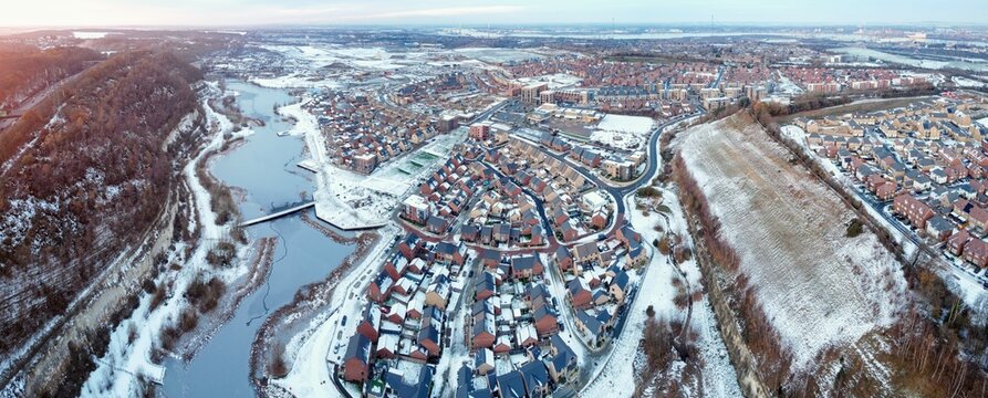 Aerial drone. Ebbsfleet garden city in Kent, covered in snow in December 2022. Aerial view of new developments and frozen lake alongside the A2 motorway.