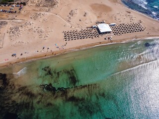 Aerial drone view of the island and beach of Isola delle Correnti with and old lighthouse surrounded by clear turquoise sea water. Southernmost point in Sicily, Portopalo di Capo Passero, Italy.