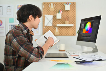 Naklejka premium Young hipster man sketch planning application process development prototype wireframe for web mobile phone at office