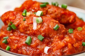 Lula kebab meat with tomato sauce sprinkled with chopped green onions, close-up, selective focus