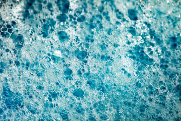 Fototapeta na wymiar Foam on surface of liquid blue detergent household chemicals, big and small foamed bubbles, close-up full depth of field, top view