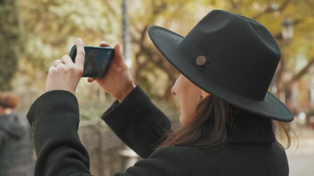 Close up footage of young tourist woman with black hat taking video with smartphone.