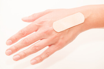 Medical band aid is glued to woman hand, selective focus
