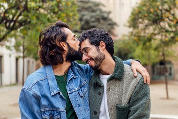 young man kissing tenderly his boyfriend's forehead, concept of urban lifestyle and love between people of the same sex