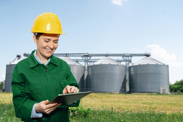 Woman engineer with a digital tablet on a background of agricultural silos for biofuel production  © scharfsinn86