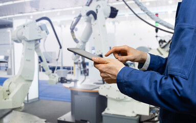 Engineer uses a digital tablet to control robots in a smart factory. Smart industry 4.0 concept	