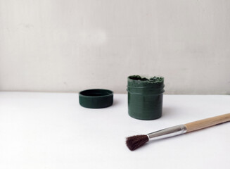 Brush and can with dark paint on a white background. The paint is open. Everything for drawing. Creation. Children are creativity. Hobby. Colored paints and gouache.