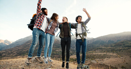 Students on adventure - Group of four emotional multiethnic friends cheering and embracing each other, having a hike vacation - friendship, emotion, travel destination 