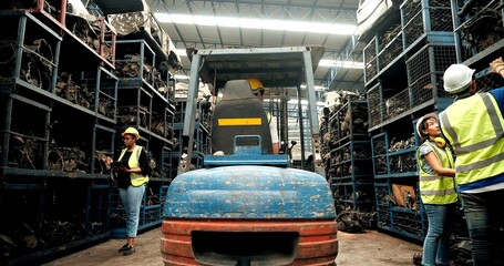 Staff workers driving forklift car checking in used automotive engine parts warehouse factory. Industrial workers concept