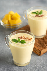 Lassi mango on a gray background. Side view, selective focus. Milkshake with mango.