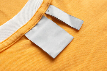 Blank white laundry care clothes label on yellow fabric texture background