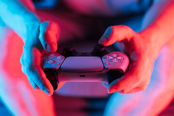 Man hands with game controller in neon light, front view