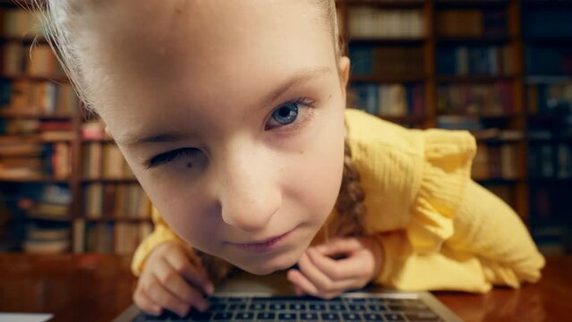 Funny little girl looking closely at laptop screen, child's curiosity, POV