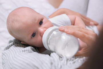 Mother feeding her little baby from bottle, closeup