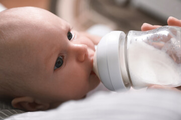 Mother feeding her little baby from bottle, closeup