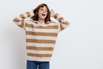 a beautiful, pleasant woman stands in a stylish striped sweater with her hands raised behind her...