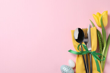 Cutlery set, Easter eggs and tulip on pale pink background, flat lay with space for text. Festive table setting
