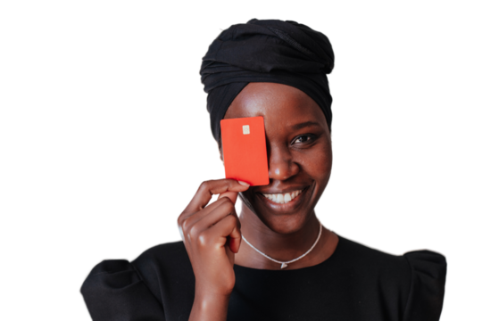 Close up portrait of African cheerful woman holding credit card, covering face, smiles against transparent background. African American young female in black turban and dress happy by receiving money