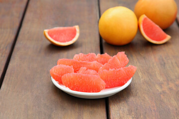 Cut and whole fresh ripe grapefruits on wooden table