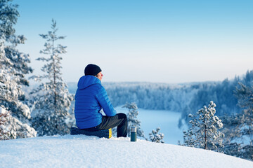 Fototapeta na wymiar A man in a blue jacket contemplates a fabulous winter landscape. Spring and summer are coming soon.