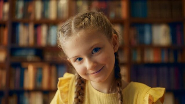 Portrait of smiling girl with blue eyes sitting in school library, childhood