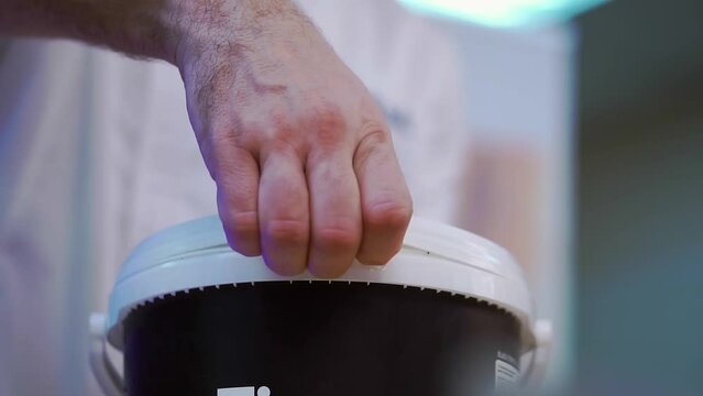 Cook opens bucket with salty sauce for spreading buns