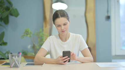 Casual Young Woman Browsing Internet on Smartphone at Work