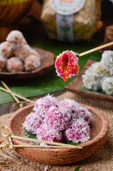 Obraz na płótnie Canvas Klepon or kelepon, is a snack of sweet rice cake balls filled with molten palm sugar and coated in grated coconut.