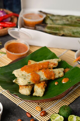 Otak-otak Tengiri with Peanut Sauce, Made from Fish and Flour, Wrap with Banana Leaves and Grill, on Wooden Table