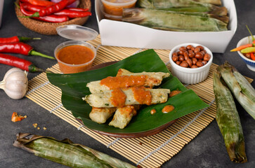 Otak-otak Tengiri with Peanut Sauce, Made from Fish and Flour, Wrap with Banana Leaves and Grill, on Wooden Table