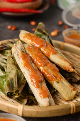 Otak-otak Tengiri with Peanut Sauce, Made from Fish and Flour, Wrap with Banana Leaves and Grill, on Wooden Table
