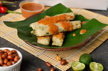 Otak-otak Tengiri with Peanut Sauce, Made from Fish and Flour, Wrap with Banana Leaves and Grill, on Wooden Table
