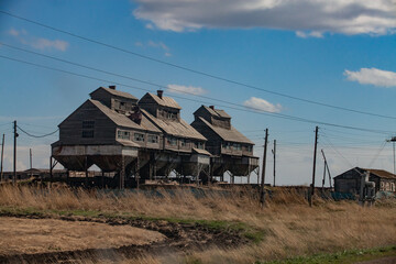 Old wooden outdated Soviet grain storage on yellow field. Cone hopper for truck loading downside....