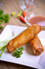 An Indonesian traditional snacks loempia or lumpia eaten with brown sauce, chili and onion  isolated on wood table
