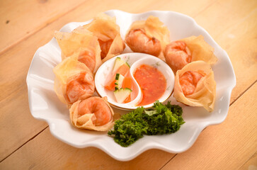 Chinese dumpling recipe called  fried wontons eated by onion sauce isolated on wood table
