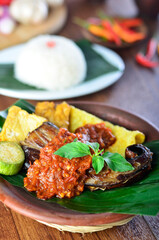 penyetan ikan tempe tahu,traditional food from Indonesia chili sambal with tempeh and tofu, wooden background,