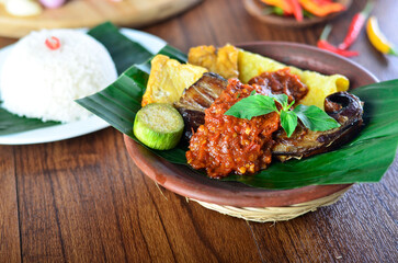 penyetan ikan tempe tahu,traditional food from Indonesia chili sambal with tempeh and tofu, wooden background,