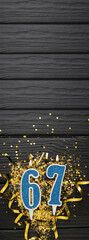Number 67 blue celebration candle and gold confetti on dark wooden background. 67th birthday card....
