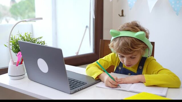 Cute smart caucasian using laptop. Online tutor teaching digital class, web lesson on computer at home. Virtual education. Schoolboy girl studying write exercise doing homework.