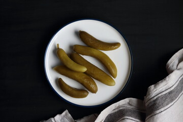 Cucumber pickles in a plate on a black background