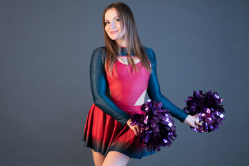 happy cheerleader girl in uniform dancing with pompoms isolated on grey background