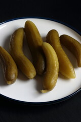 Cucumber pickles in a plate on a black background