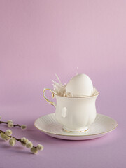 white tea cup white Easter egg on pink background 