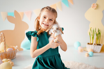 Happy cute little girl holds fluffy rabbit on Easter colorful decor background. Easter concept 