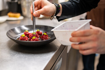 professional chef's hands cooking Raw beef meat tartar in restaurant kitchen