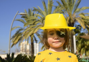 A cute boy with a black pirate eye patch. Palm trees in the background - concept: sea vacation,...