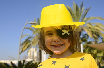 A cute boy with a black pirate eye patch. Palm trees in the background - concept: sea vacation,...